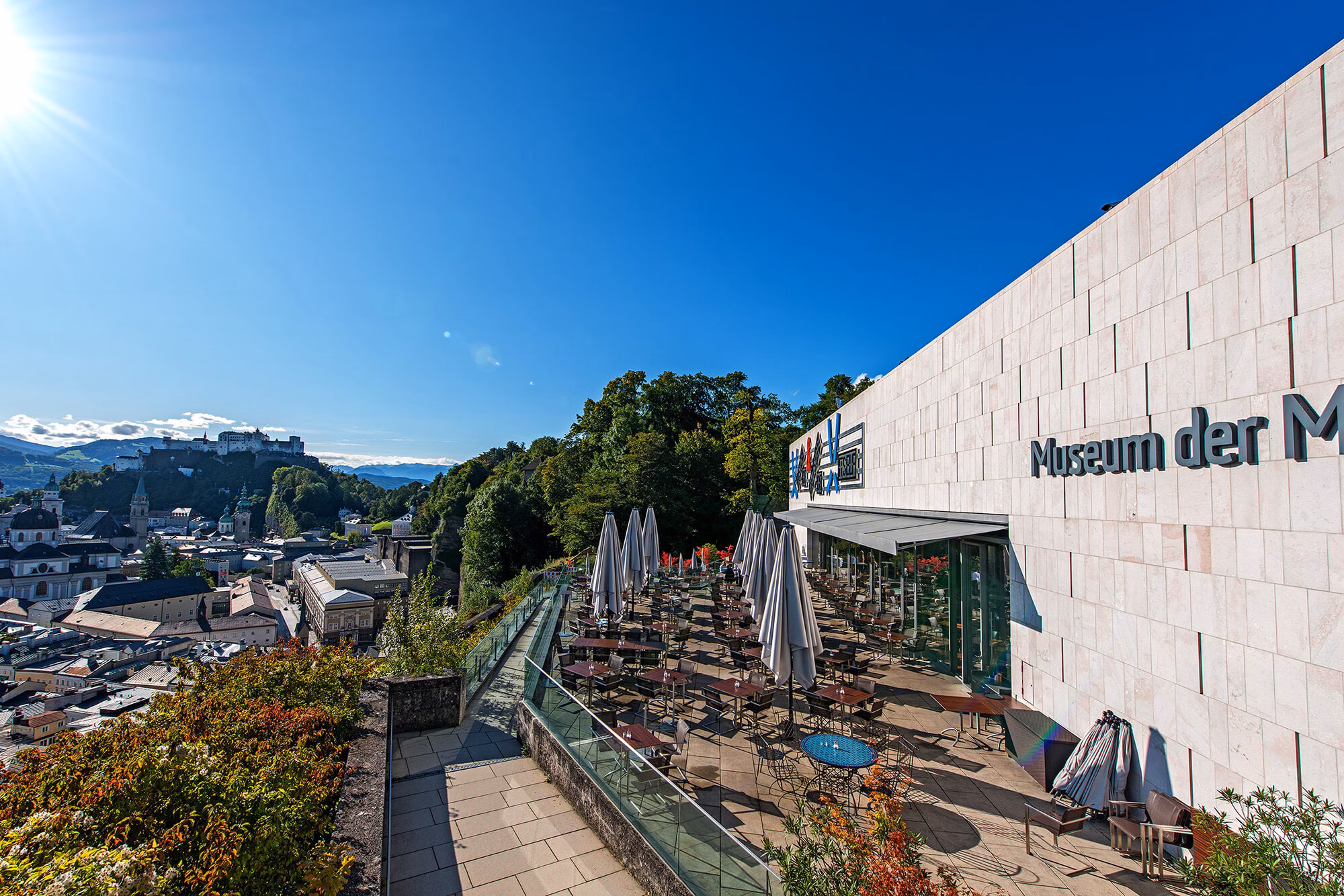 View from the Museum of Modern Art Mönchsberg over Salzburg’s old town with rooftops, churches, and mountains in the background.
