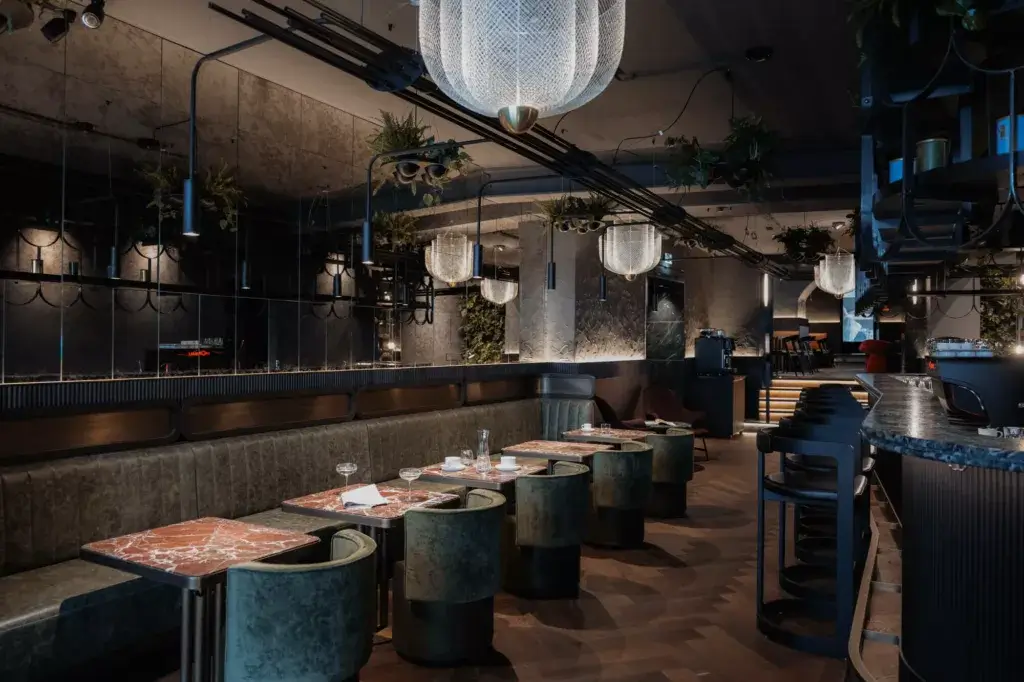 A view into the bar area with designer elements, including sleek marble tables and elegant velvet chairs.