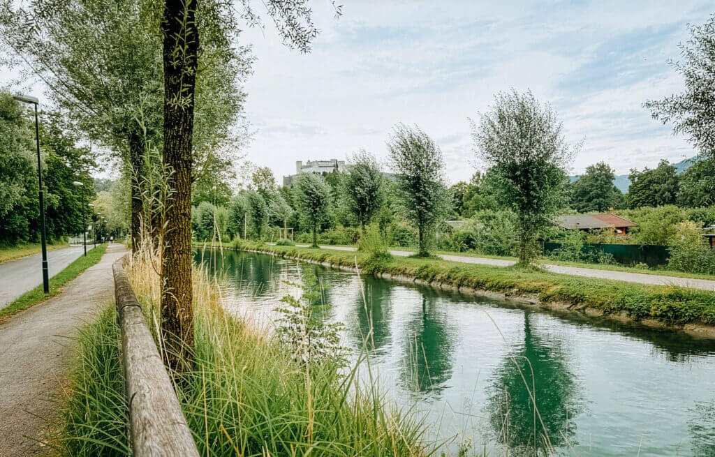Salzburg canal waterway with trees and a castle in the distance.