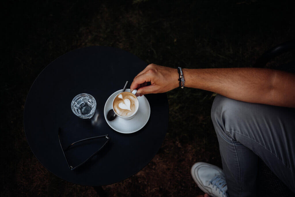 Man's hand reaching for a latte with heart art in a garden sanctuary