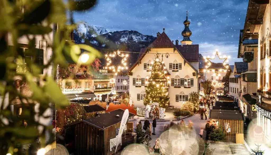 A festive Christmas market in St. Gilgen at Lake Wolfgangsee, with charming wooden stalls offering local crafts, food, and holiday treats. The market is set against the backdrop of the lake and snow-covered mountains, creating a picturesque and cozy winter atmosphere.
