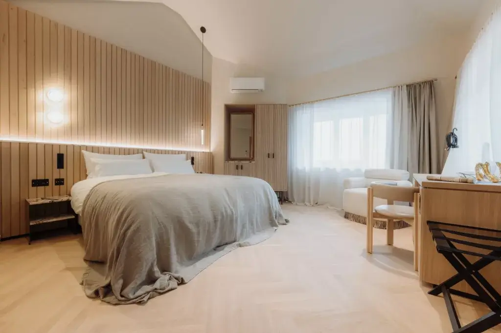 Luxury hotel room with king-size bed, modern wood paneling, and a comfortable armchair.