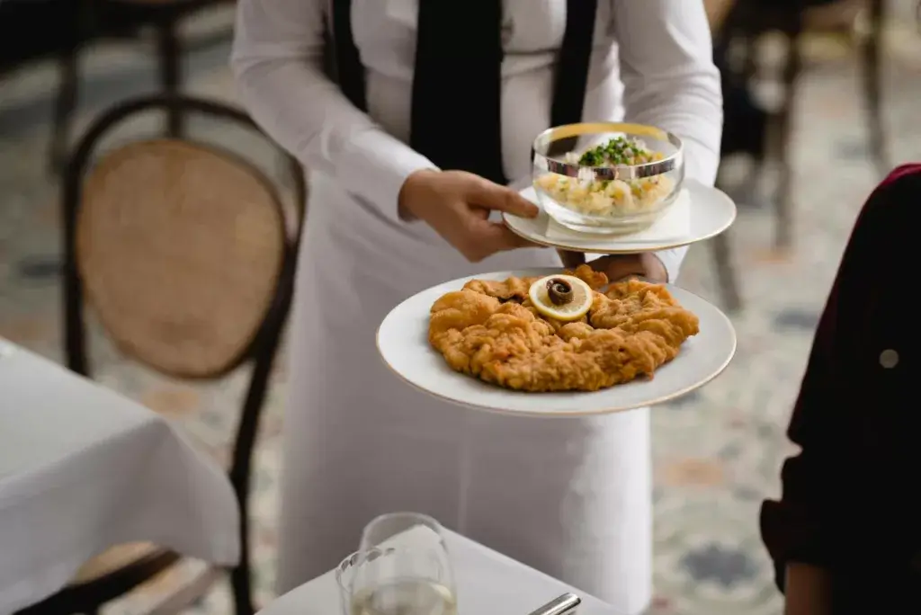 A classic plate of original Austrian schnitzel, perfectly breaded and golden-brown, served alongside a traditional potato salad. The schnitzel is tender and crispy, while the potato salad is creamy with a hint of tang, creating a deliciously authentic Austrian dish.