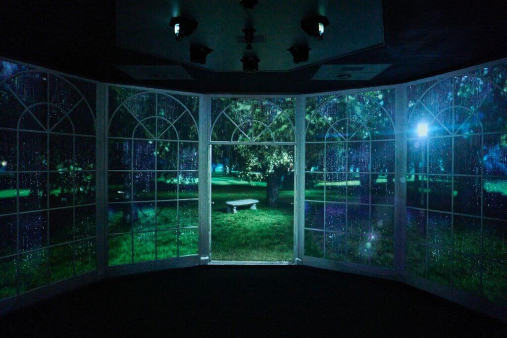 Projected rain on a garden scene viewed through a large window