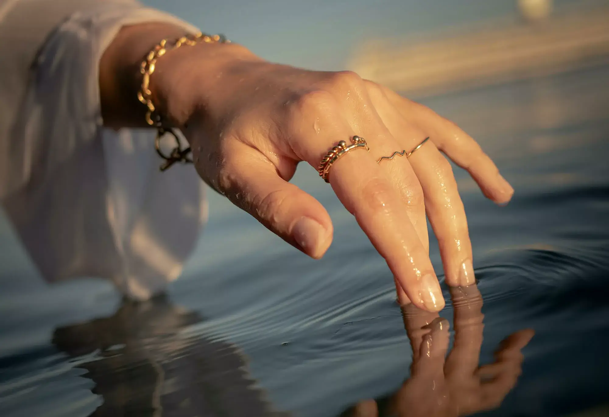 A woman delicately dips her finger into a lake in Salzburg, enjoying the serene beauty and tranquility of the natural surroundings.